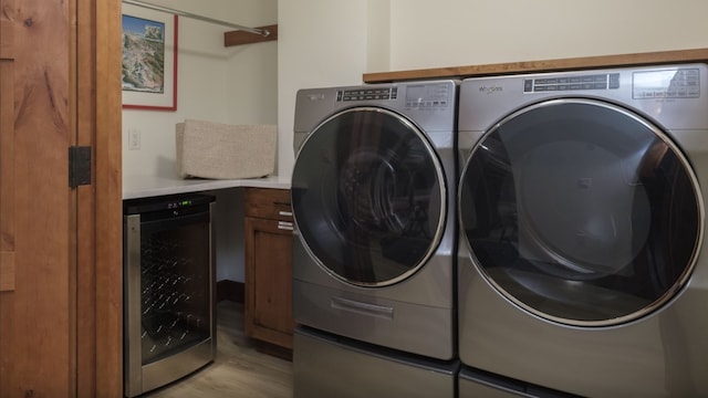 clothes washing area featuring wine cooler, cabinets, separate washer and dryer, and light hardwood / wood-style floors