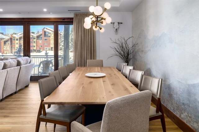 dining area with a notable chandelier and light hardwood / wood-style flooring