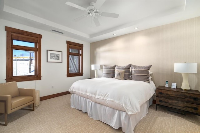 bedroom featuring light colored carpet, ceiling fan, and a tray ceiling