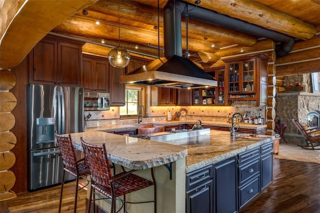 kitchen with beam ceiling, rustic walls, a spacious island, and appliances with stainless steel finishes