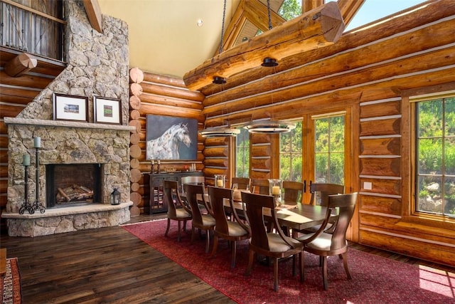 dining space featuring hardwood / wood-style flooring, rustic walls, a fireplace, and high vaulted ceiling