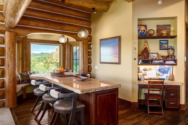 interior space with rustic walls, light stone counters, dark wood-type flooring, and pendant lighting