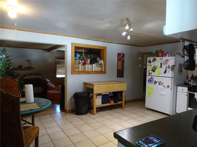 kitchen with white refrigerator, ornamental molding, and light tile patterned floors