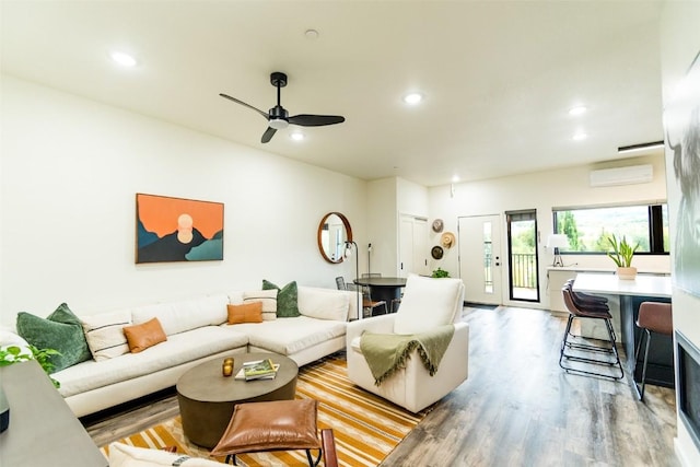 living room with ceiling fan, a wall mounted AC, and light hardwood / wood-style flooring