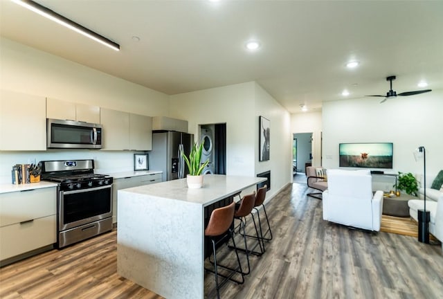 kitchen featuring ceiling fan, dark hardwood / wood-style flooring, a kitchen bar, a kitchen island, and appliances with stainless steel finishes