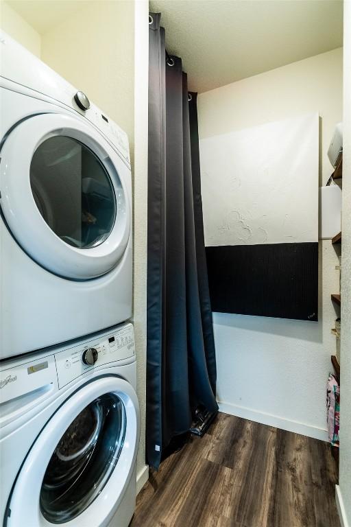 washroom with stacked washer and dryer and dark wood-type flooring