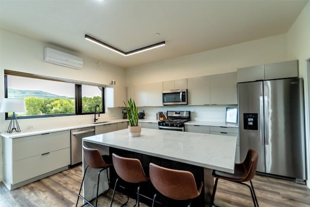 kitchen featuring a wall unit AC, a center island, a breakfast bar area, and appliances with stainless steel finishes