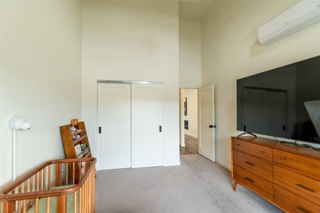 carpeted bedroom with a wall mounted AC, a towering ceiling, a nursery area, and a closet