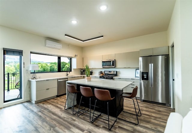 kitchen featuring sink, a breakfast bar area, a kitchen island, stainless steel appliances, and a wall unit AC