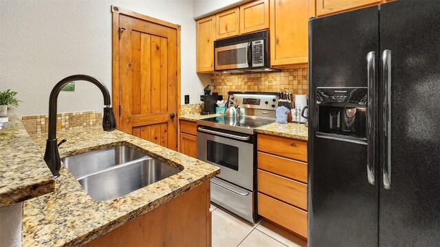 kitchen with light tile patterned flooring, sink, tasteful backsplash, light stone counters, and stainless steel appliances