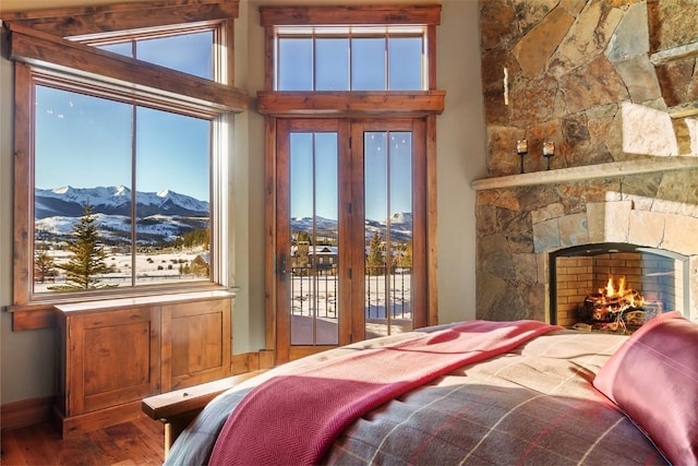 bedroom featuring hardwood / wood-style floors, a mountain view, a fireplace, and access to outside