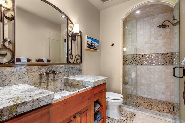 bathroom with vanity, tile patterned flooring, toilet, walk in shower, and tasteful backsplash