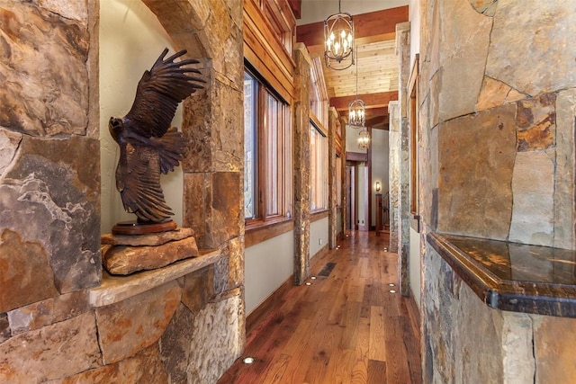 corridor with dark hardwood / wood-style flooring and an inviting chandelier