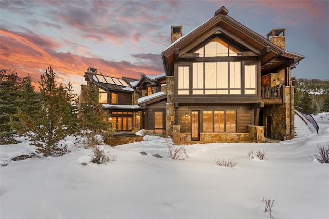 snow covered rear of property with a balcony