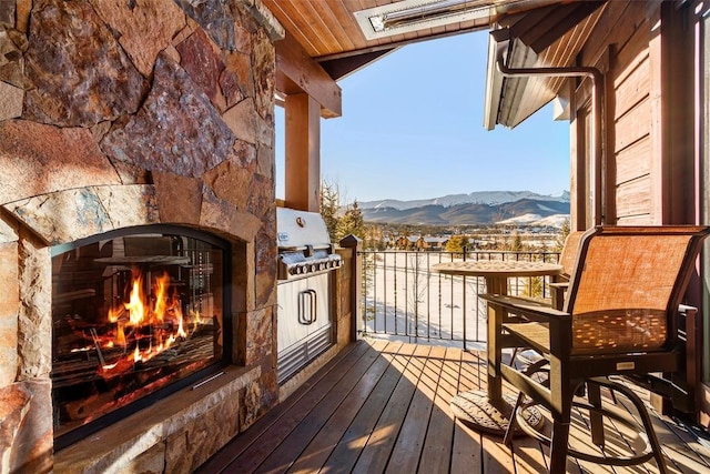 balcony with an outdoor stone fireplace, area for grilling, and a mountain view