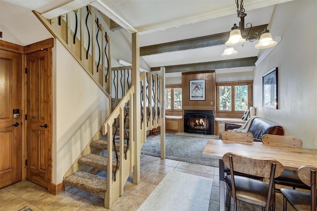 interior space featuring a warm lit fireplace, light tile patterned flooring, light colored carpet, stairs, and beamed ceiling