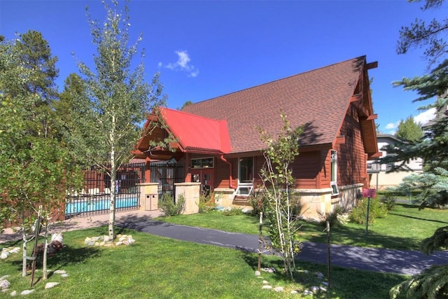 view of front of house with a fenced in pool, fence, and a front lawn