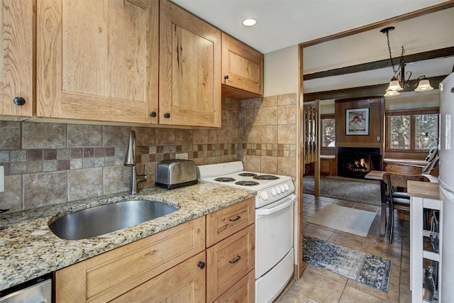 kitchen with light stone counters, white electric range oven, hanging light fixtures, a sink, and a lit fireplace