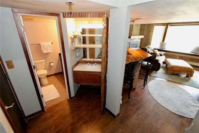 bathroom with baseboards, toilet, wood finished floors, vanity, and a fireplace