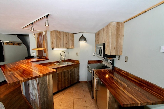 kitchen with stainless steel appliances, butcher block counters, light tile patterned flooring, a sink, and a peninsula