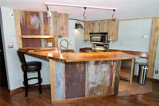 kitchen with a sink, wood counters, stainless steel appliances, and wood finished floors