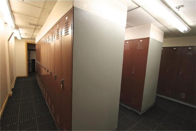 hall featuring a drop ceiling, baseboards, and tile patterned floors