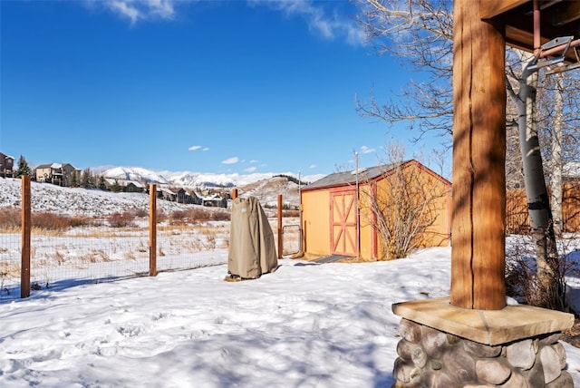 yard layered in snow with a mountain view and a storage shed