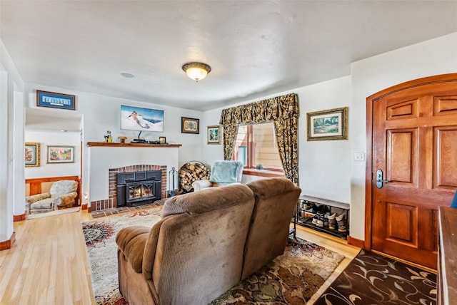 living room with a brick fireplace and hardwood / wood-style flooring