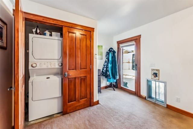 clothes washing area with stacked washing maching and dryer and light carpet