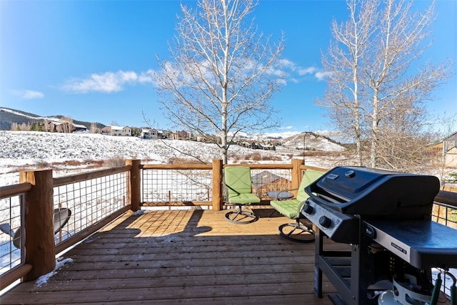 snow covered deck with grilling area and a mountain view