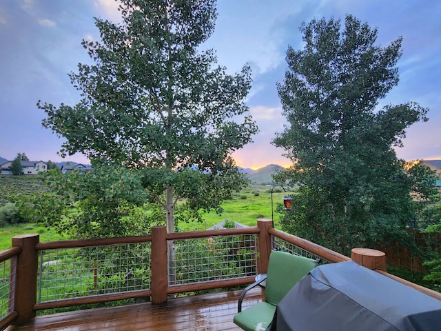 deck at dusk with a mountain view and a grill