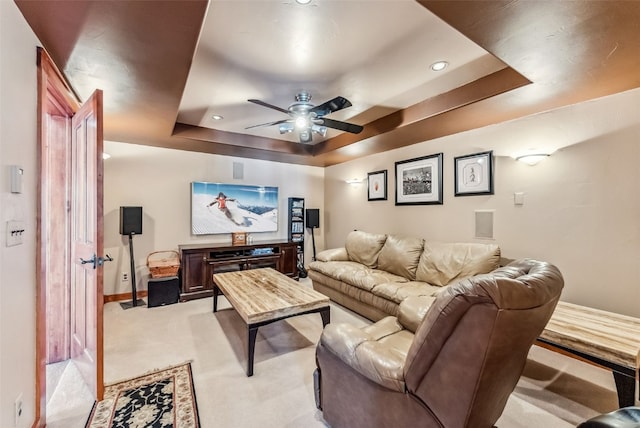 carpeted home theater room featuring ceiling fan and a raised ceiling