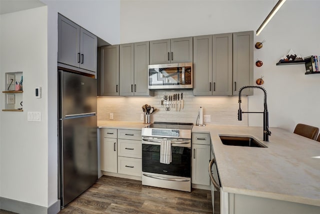 kitchen featuring gray cabinets, appliances with stainless steel finishes, tasteful backsplash, sink, and dark wood-type flooring