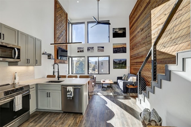 kitchen featuring stainless steel appliances, kitchen peninsula, sink, and gray cabinetry