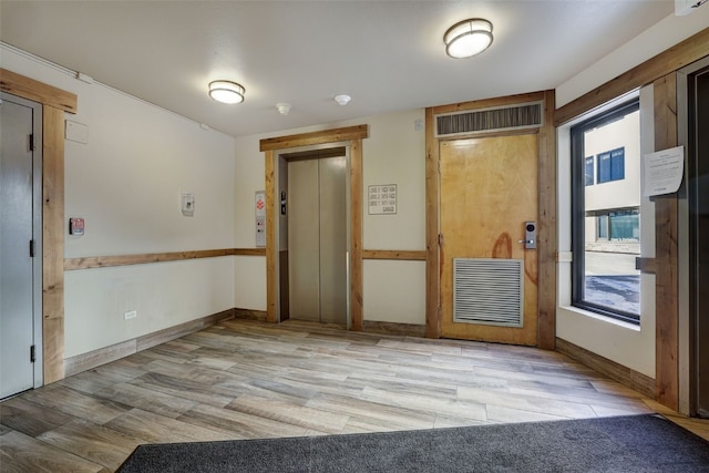 spare room featuring elevator and light hardwood / wood-style flooring