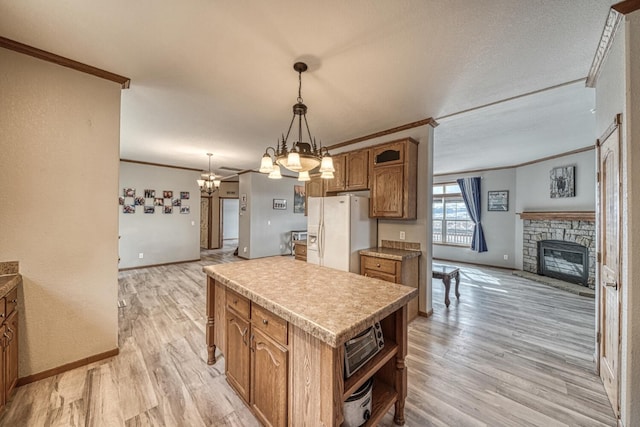 kitchen featuring a fireplace, crown molding, light wood finished floors, open floor plan, and white fridge with ice dispenser