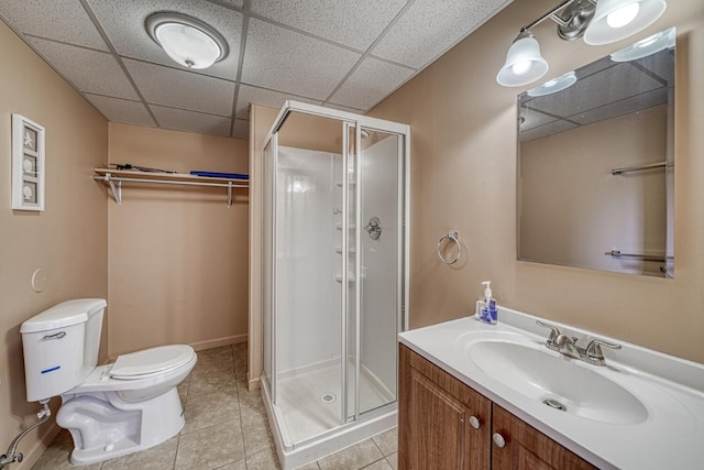 full bath with a drop ceiling, toilet, vanity, tile patterned floors, and a stall shower