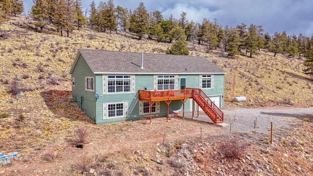 back of property featuring an attached garage, driveway, stairs, and a deck