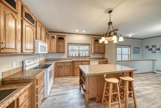 kitchen with white appliances, brown cabinetry, light wood-style flooring, glass insert cabinets, and a center island