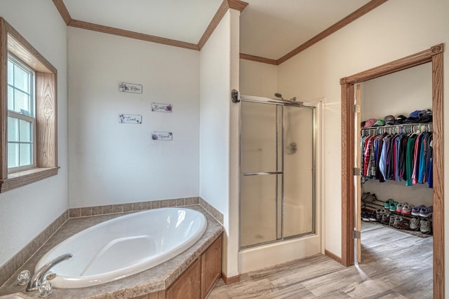 bathroom with wood finished floors, ornamental molding, a shower stall, and a bath