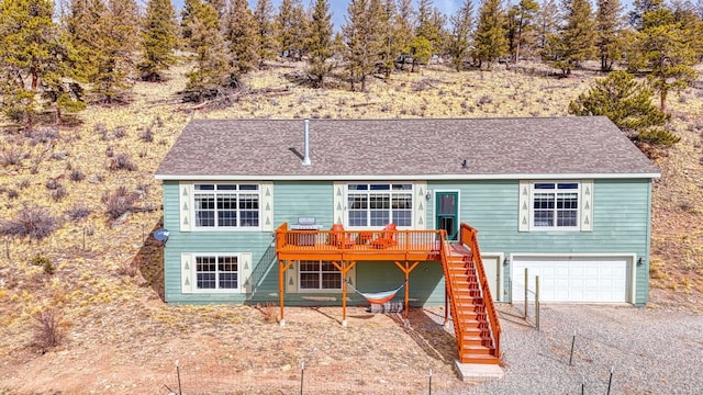 rear view of property with a garage, a shingled roof, stairway, and a deck