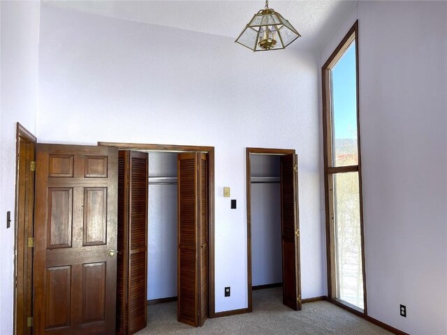 unfurnished bedroom featuring carpet flooring, two closets, and a notable chandelier