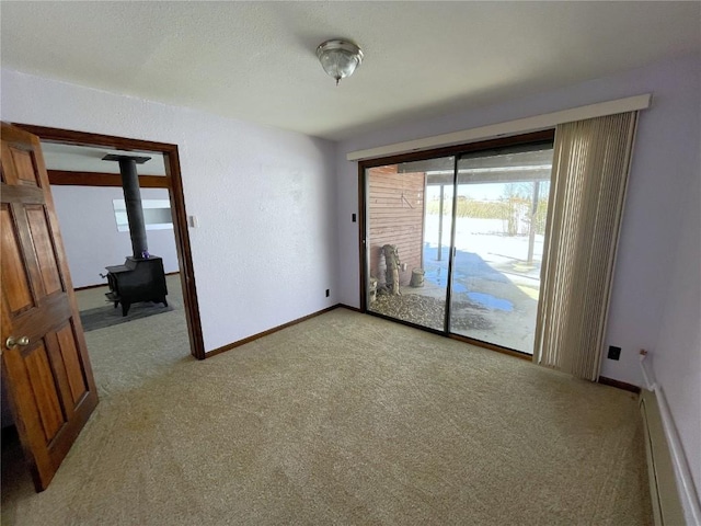 carpeted spare room with a baseboard heating unit