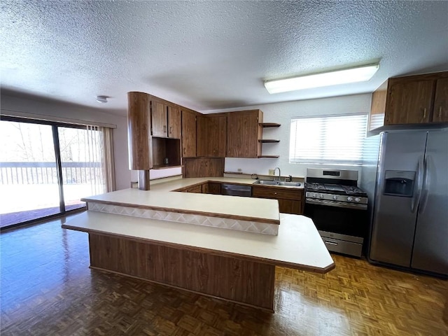 kitchen with kitchen peninsula, a breakfast bar, stainless steel appliances, and a textured ceiling