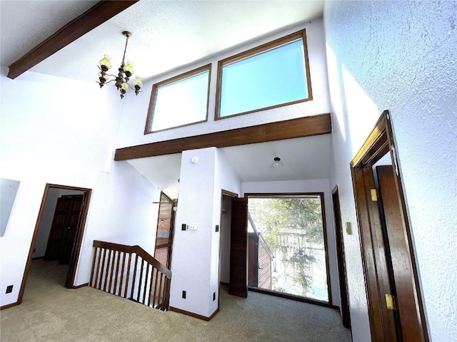 interior space with carpet, beam ceiling, high vaulted ceiling, and an inviting chandelier