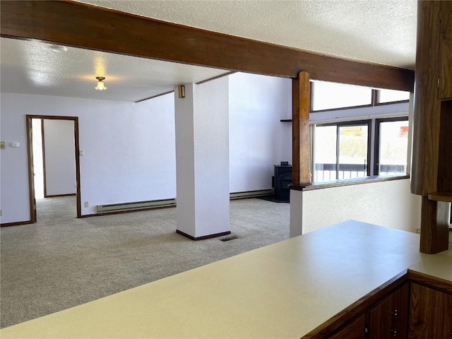 interior space featuring light carpet, a textured ceiling, a baseboard radiator, and a wood stove