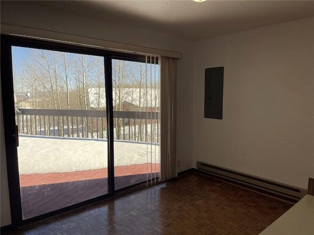 spare room featuring dark parquet flooring, electric panel, and a baseboard heating unit