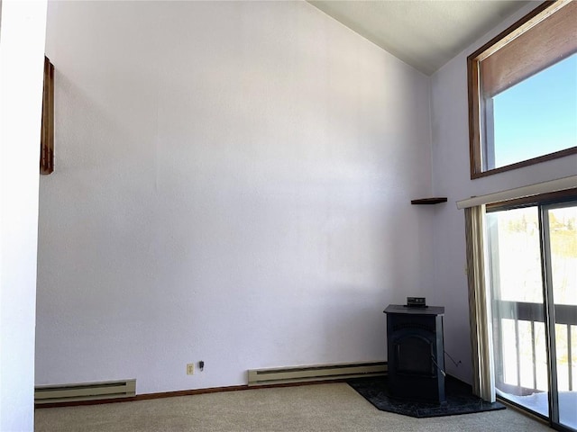 unfurnished room with carpet flooring, a wood stove, a baseboard radiator, and lofted ceiling