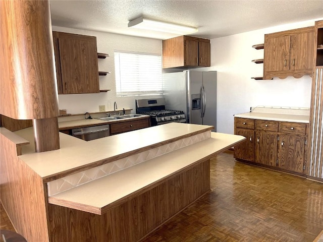 kitchen with kitchen peninsula, a textured ceiling, stainless steel appliances, dark parquet floors, and sink