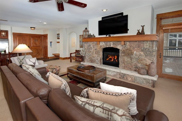 living room with ceiling fan, a stone fireplace, and carpet